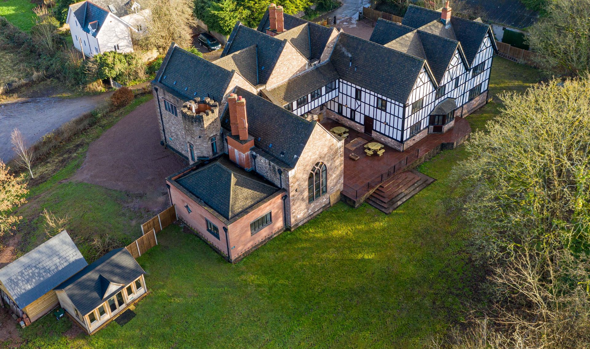 Drone View showing the Hot Tub room, patio area, Tudor inspired side of the house and the large arch window at the Manor on the Monnow Holiday accommodation Monmouthshire www.bhhl.co.uk